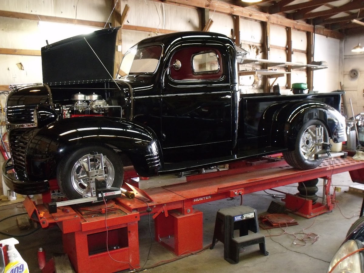 A classic black pickup truck on the alignment rack inside the Beach Automotive shop
